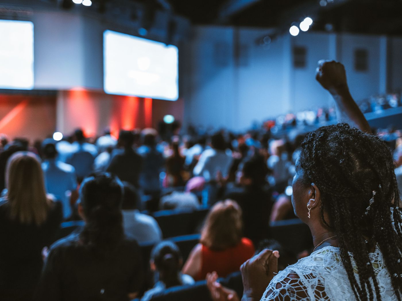 A conference audience facing a stage screen